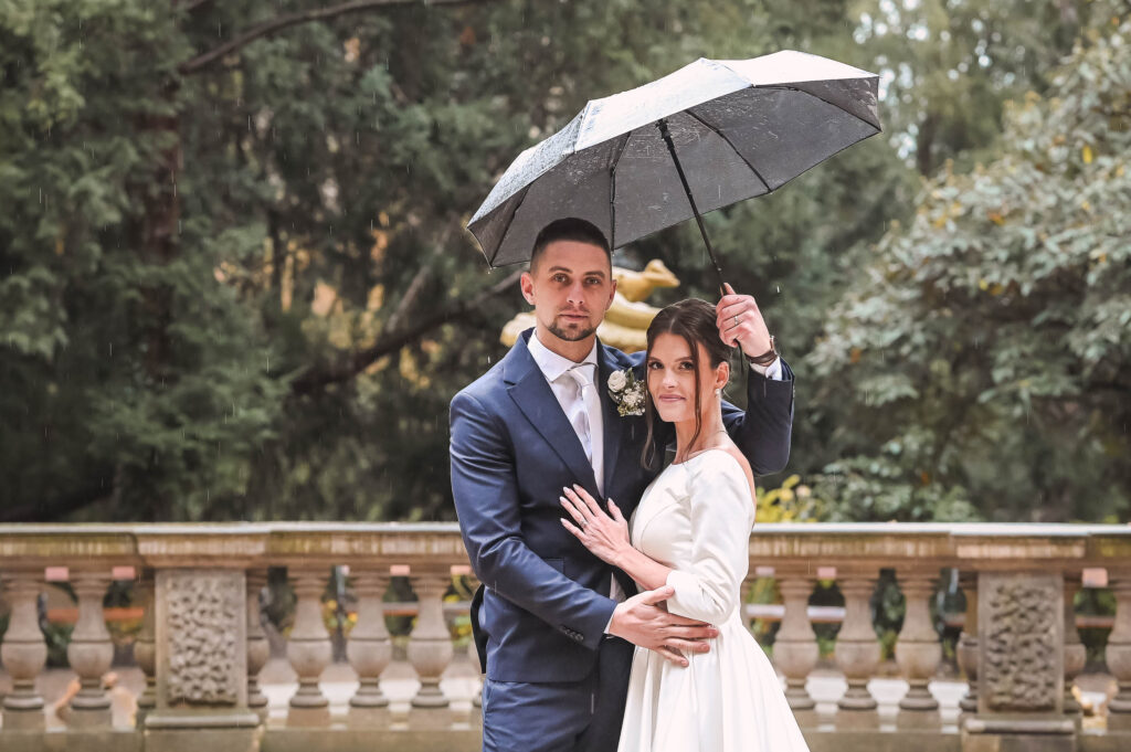Novomanželé ve větru drží deštník, který jim téměř odlétá, foceno v Grébovce